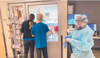  ?? ANDREW SELSKY/AP ?? Visitors peer into the room of a COVID-19 patient last week at Salem Hospital in Oregon as a nurse dons protective gear before going into the room of another patient. The highly contagious delta variant is hammering the state.