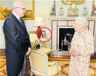  ?? Picture: JOHN STILLWELL ?? The Queen greets George Brandis with portrait in the background (circled) yesterday