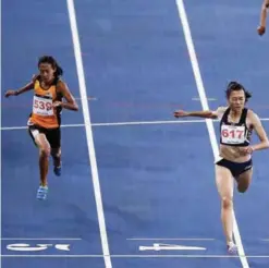  ?? — AFP ?? KUALA LUMPUR: Vietnam’s Le Tu Chinh (left) crosses the finish line first to win the women’s 200m athletics final of the 29th Southeast Asian Games (SEA Games) at the Bukit Jalil national stadium in Kuala Lumpur yesterday.