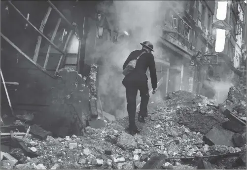  ?? PICTURE: WILLIAM VANDERSON/ FOX PHOTOS/ GETTY IMAGES. ?? REAL THREAT: A warden picking his way through the rubble and inspecting the damage after a German bombing raid.