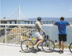  ?? BRIAN FEULNER ?? Cyclists look out over the Bay Bridge toward Oakland after crossing the bridges bike path from Oakland to Treasure Island.