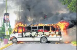  ??  ?? ■ A burning bus, set alight by cartel gunmen to block a road, is pictured during clashes with security forces in Culiacan, Mexico; (right) a bullet-ridden window of a vehicle.