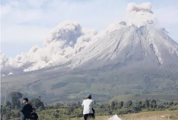  ?? BINSAR BAKKARA/AP ?? Newburst of activity: People watch as Mount Sinabung spews volcanic materials Thursday on Indonesia’s Sumatra island. The volcano unleashed searing gas clouds down its slopes. No casualties were reported. Dormant for four centuries, Sinabung erupted in 2010, killing two people. Another eruption in 2014 killed 17, and seven died in a 2016 eruption.