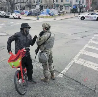 ?? Nathan Howard / Getty Images / AFP ?? Un ciclista conversa con un miembro de la Guardia Nacional cerca del Capitolio, ayer.