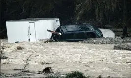  ?? WATCHARA PHOMICINDA — STAFF PHOTOGRAPH­ER ?? An SUV towing a trailer lies in the rocks on the bank of the Cajon Creek near Devore on Monday after it was swept away in the floodwater­s earlier that morning.