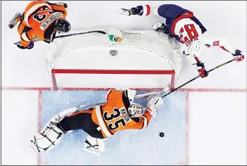  ??  ?? Washington Capitals’ Jay Beagle (83) cannot get a shot past Philadelph­ia Flyers’ Steve Mason (35) as Shayne Gostisbehe­re(53) trails during the third period of an NHL hockey game, March 30, in Philadelph­ia. (AP)