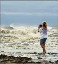  ?? GUISEPPE BARRANCO — THE BEAUMONT ENTERPRISE VIA AP ?? Tricia Hayes records images of unusually large waves created by Tropical Storm Cindy on Bolivar Peninsula, Texas, Wednesday. Texas Gov. Greg Abbott has ordered the State Operations Center to raise its readiness level. He also activated four Texas Task...