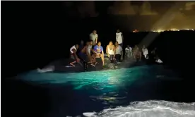  ?? Photograph: Royal Bahamas Defence Force/ Reuters ?? Survivors of a migrant boat that capsized perch on the overturned vessel off the coast of New Providence island, Bahamas, on Sunday.