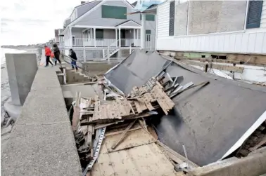  ?? THE ASSOCIATED PRESS ?? People step onto a seawall near damaged beachfront homes Sunday in Marshfield, Mass. The Northeast is bracing for its third nor’easter in fewer than two weeks. The National Weather Service reported Sunday that a storm was expected to make its way up...