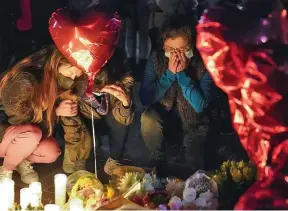  ?? Photo: AP ?? Women pause at a memorial at a vigil honoring the victims of a shooting at the Star Ballroom Dance Studio on January 23, 2023, in Monterey Park, Californin­a.
