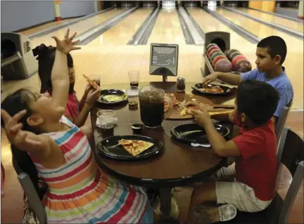  ?? VINCENT OSUNA PHOTO ?? Melanie, 6, Sophia, 7, Jesus, 9, and Adriel Castillo, 5, enjoy pizza in between their next game of bowling during a soft opening held Saturday at StrikeZone IV in El Centro.