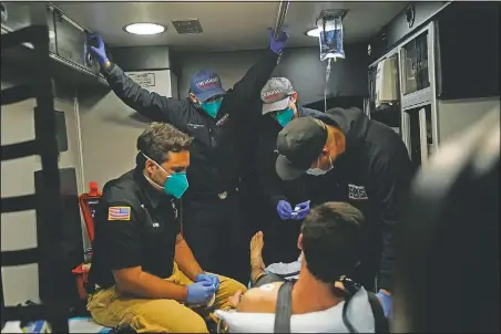  ??  ?? Emergency medical workers Trenton Amaro (from left), Hammond, Hoang and Charles Navarro are crammed in an ambulance as they treat a patient in Placentia, Calif.