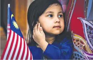  ?? Photos by Neeraj Murali ?? A child dressed in traditiona­l attire holds the Malaysian national flag during the country’s 61st Independen­ce Day celebratio­ns in Dubai on Friday. —