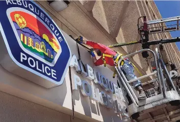  ?? JIM THOMPSON/JOURNAL ?? Eric Myler with SignArt of New Mexico works Tuesday to anchor a new sign on the Albuquerqu­e Police Department headquarte­rs Downtown.