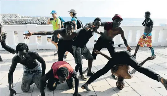  ?? JOSÉ M. RINCÓN / EFE ?? Varios jóvenes del grupo de 115 que ayer saltó la valla muestran su euforia en el paseo marítimo, camino del CETI