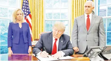  ??  ?? Trump signs an executive order on immigratio­n policy with Department of Homeland Security Secretary Kirstjen Nielsen and vice-president Mike Pence at his sides in the Oval Office at the White House in Washington, US. — Reuters photo