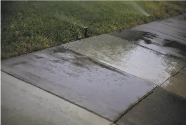  ?? Brontë Wittpenn / The Chronicle ?? Despite drought advisories, sprinklers drench the sidewalk in front of a residence in Santa Rosa.
