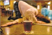  ??  ?? A brew is always nearby during a Beer Yoga class. “Anything with alcohol and exercise is a novelty, you know?” says participan­t Anastasia Billings of Oakley.