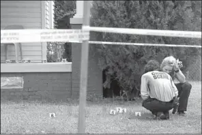  ?? Arkansas Democrat-Gazette/BENJAMIN KRAIN ?? Little Rock crime scene investigat­ors search for bullet casings on the porch and yard of a home at West 27th and Washington streets, where two 16-year-olds were shot Sunday.