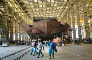  ?? TED JACKSON/AP ?? Workers pass the stern of the unfinished 260-foot-long Eco Edison ship Monday in Terrebonne Parish, La.