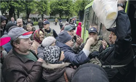  ?? EVGENIY MALOLETKA, THE ASSOCIATED PRESS ?? A police officer distribute­s humanitari­an aid to local residents in Lyman, Donetsk region, Ukraine.