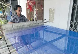  ??  ?? A skilled weaver works her loom to create a silk cloth using locally spun thread.