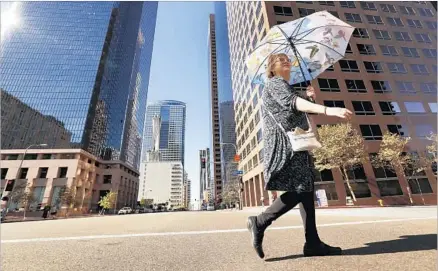  ?? Al Seib Los Angeles Times ?? TERRIE LEE DUBA tries to shade herself from the sun on her way to catch a bus in downtown Los Angeles, where temperatur­es Monday reached 104 degrees. Across the region, temperatur­es were some 20 degrees higher than average, prompting fire concerns.