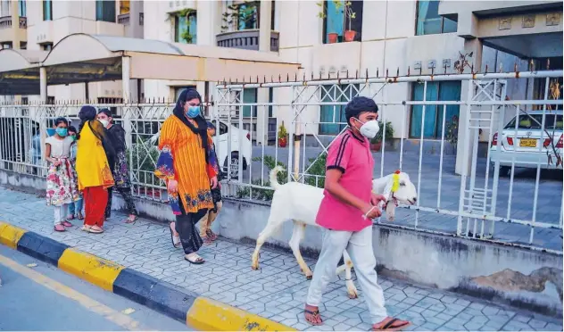  ?? Agence France-presse ?? ↑
Children wearing face masks walk with a goat ahead of Eid Al Adha in Rawalpindi on Thursday.