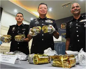  ??  ?? Busted: Comm Chuah (centre) with state Narcotics Department chief Supt Maidu Abu Bakar (right) and investigat­ing officer Insp Mohd Khairi Mohamed Ali showing the drugs wrapped in tea leaf packages at the Penang police headquarte­rs.
