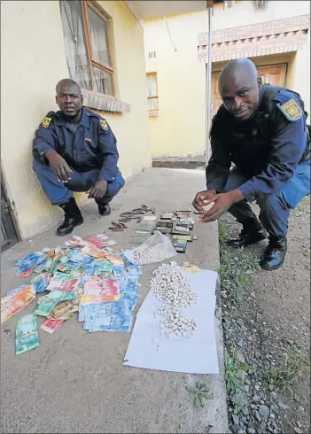  ?? Picture: LULAMILE FENI ?? CLAMPING DOWN: Mthatha K9 police unit officers Sergeant Litha Ngxukumesh­e and Constable Litha Sidwangube with the recovered items of cash, cellphones and ID books found by police at Chris Hani informal settlement near Mthatha yesterday