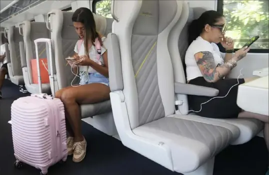  ?? Marta Lavandier/Associated Press ?? Brightline passengers look at their phones Sept. 8 in Aventura, Fla. Brightline is launching a new route from Miami to Orlando on Friday.