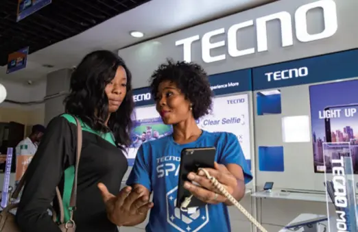  ??  ?? A seller shows a TECNO phone to a customer in Lagos, Nigeria, in October 2018