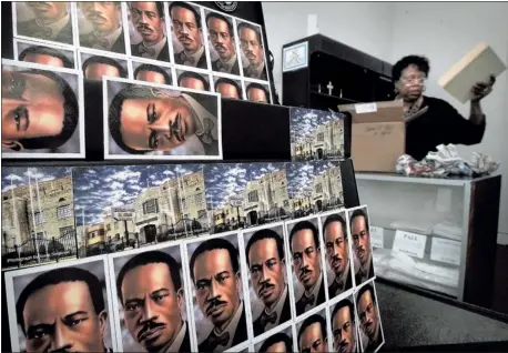  ?? PHOTOS BY JIM WEBER/THE COMMERCIAL APPEAL ?? Magnets with the likeness of Church of God in Christ founder Bishop C.H. Mason decorate a display at the COGIC Bookstore on Main Street, where manager Sharon Miller unpacks a new Bible- embossing machine. In a market where many secular bookstores are...