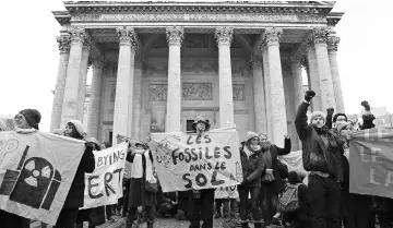  ??  ?? People hold signs reading ‘Fossil fuel on the ground’ during a demonstrat­ion called by NGOs outside the Pantheon in Paris on the sidelines of the ‘One Planet Summit – Public and private finance in support of climate action’ in Boulogne, Paris’...