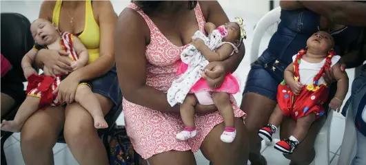  ?? CREDIT: MARIO TAMA / GETTY IMAGES ?? Babies born with microcepha­ly are held by their mothers at a Carnival party held last February in a health clinic in Pernambuco state, Brazil.