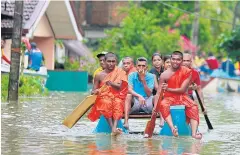  ??  ?? KEEPING AFLOAT: Monks and villagers travel in a raft in a flooded area in Sri Lanka. The country has appealed for outside help as dozens were killed in floods and landslides.