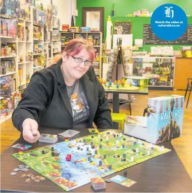  ?? Picture / Mark Mitchell ?? Susan Wells with one of her favourite board games, Raiders of the North Sea, in Caffeinate­d Dragon Games.