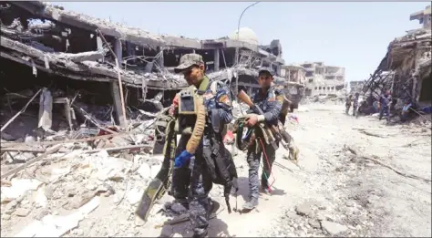  ??  ?? Members of Iraqi Federal police carry suicide belts used by Islamic State militants in the Old City of Mosul, Iraq, yesterday.