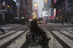  ?? EDUARDO MUNOZ ALVAREZ/AFP VIA GETTY IMAGES ?? A man on a wheelchair crosses a street under a snowfall in New York City’s Times Square during a winter storm on Jan. 7, 2017 in New York.