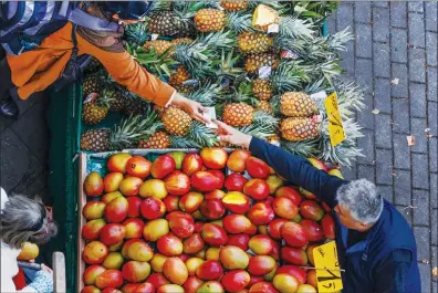  ?? Photo: VCG ?? A shopper buys pineapples at a fruit and vegetable market in Berlin on October 14, 2022. Inflation will hit 8 percent in 2022 and 7 percent in 2023, the German government forecast. The government recently unveiled a 200-billion-euro fund to shield consumers and businesses from surging prices, which includes a cap on energy costs.