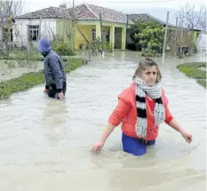  ?? HEKTOR PUSTINA/THE ASSOCIATED PRESS ?? A woman and her son leave their flooded home after heavy rainfall in the village of Hasan, about 25 km north of Tirana, Albania, on Friday. At least one person has died during heavy rainfall that flooded many parts of Albania, paralyzing its ports and...