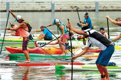  ?? STAFF PHOTOS BY DOUG STRICKLAND ?? Paddlers race Thursday on the Tennessee River near the Market Street Bridge in Chattanoog­a. Paddling sports are growing in popularity, and state officials want paddlers to enjoy the sport safely.