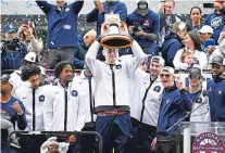  ?? JESSICA HILL/THE ASSOCIATED PRESS ?? UConn’s Donovan Clingan holds the championsh­ip trophy with coaches and teammates during a parade to celebrate the men’s basketball title Saturday in Hartford, Conn.