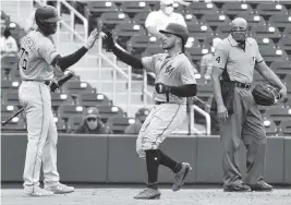  ?? ERIC ESPADA Getty Images ?? Isan Diaz, getting a high-five from Jesus Sanchez after scoring a run, has extra-base hits in his past two spring games. He is vying with Jazz Chisholm to start at second base.