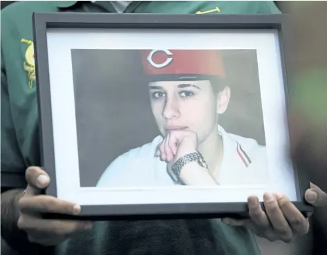  ?? CANADIAN PRESS FILES ?? A photo of Sammy Yatim is held by one of the teen’s friends at a Toronto courthouse after the sentencing of Const. James Forcillo in Toronto on Thursday. Forcillio was sentenced to six years for attempted murder on Thursday, but was granted bail on...