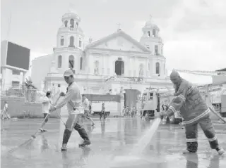  ?? PHOTO BY JESSIE LAURETA ?? A fireman and volunteers from Manila city hall clean Plaza Miranda in the city’s Quiapo district on Tuesday.