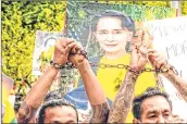  ?? AFP ?? Myanmar migrants in Thailand hold up the three finger salute and a picture of detained Myanmar civilian leader Aung San Suu Kyi at a protest against the military coup in their home country, in front of the United Nations ESCAP building in Bangkok .