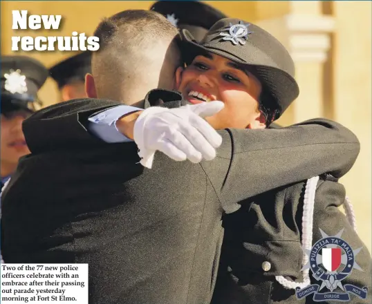  ??  ?? Two of the 77 new police officers celebrate with an embrace after their passing out parade yesterday morning at Fort St Elmo.