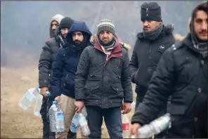  ?? (AP/BelTA/Leonid Shcheglov) ?? Migrants line up to collect drinking water Friday as they gather at the Belarus-Poland border near Grodno, Belarus.