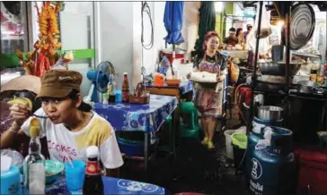  ?? SUWANRUMPH­A/AFP LILLIAN ?? A woman arranges fried snacks on her street food cart in the Pratunam district of Bangkok yesterday.